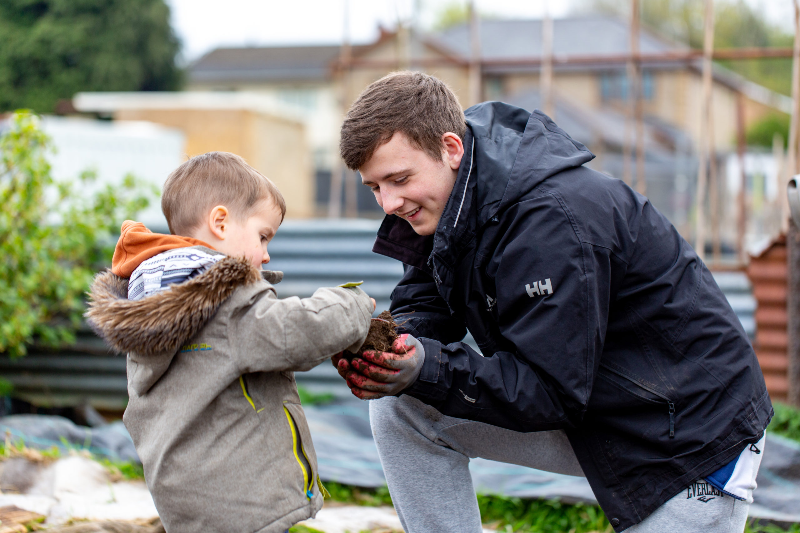Teenage boy helping young boy with gardening